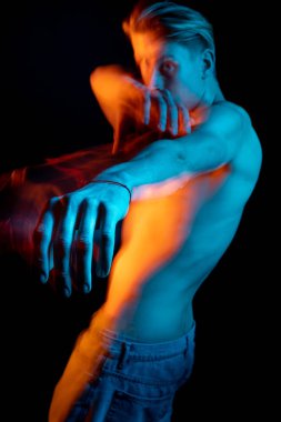 Odaklan. Elini uzat. Genç bir adamın portresi. Mavi ve turuncu tamamlayıcı renkler. Yaratıcı uzun pozlama fotoğrafları serisi kinayeli mecazi duygu gösterimi.  