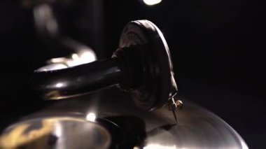 Atmosferik klasik müzik aleti. Dönen bir disk üzerinde gramofon iğnesi. Eski tarz vinil çalar. Video görüntüleri. Retro disk oynatıcıyı kapatma işlemi devam ediyor. Siyah arka plan. Arkaplan