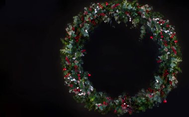 Kırmızı yay ve önemsiz şey süslemeleri, holly, ökse otu ve kış yeşil koyu mavi meşe ön kapı arka plan üzerinde Noel çelenk.