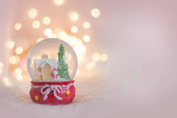 Açık pembe renkli ve hatıra kar küresi olan bir Noel kartı için arka plan