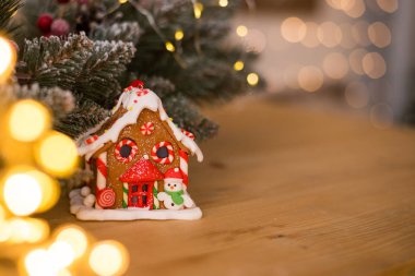 Zencefilli kek evi. Güzel bir hatıra. Hediye. Bulanık Noel ışıklarının arka planına karşı ahşap bir yüzeyde.