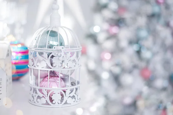 Karácsonyi játékok labdák ezüst kék rózsaszín fehér nyílászáró ketrec a háttérben a karácsonyi fények. — Stock Fotó