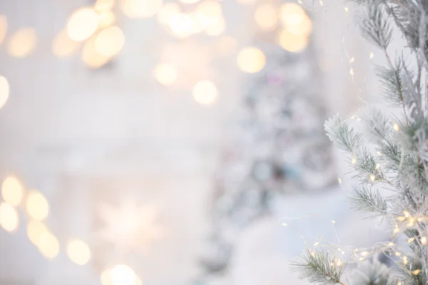 Yeni yılın gümüş parlak topu köknar dalında asılı duruyor. Gri bir arka planda ışıklar ve çelenkler. Noel ve mutlu yıllar konsepti, tasarımınız için metin alanı.