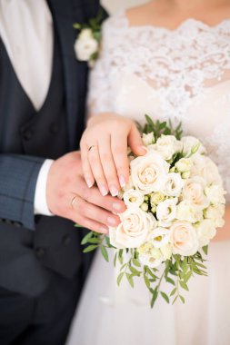 Gelin ve damadın elleri düğün buketinde yüzüklerle. Evlilik kavramı.
