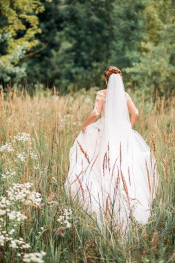 Güzel deniz manzarası ve gün batımında dağların üzerinde düğün buketiyle duran şık gelin.