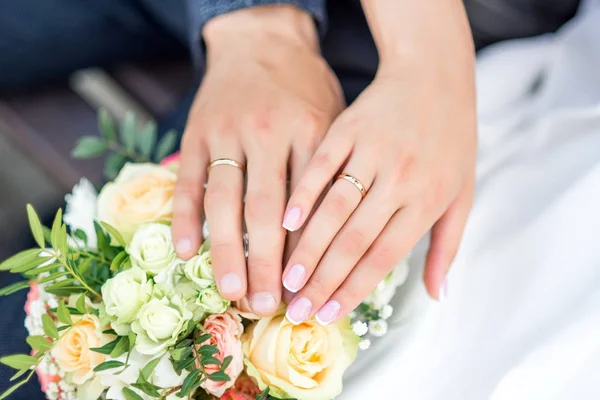 Hände von Braut und Bräutigam mit Ringen am Brautstrauß. Ehekonzept. — Stockfoto