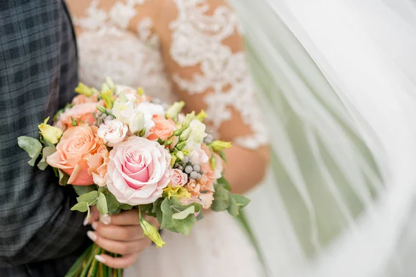 Νύφη και γαμπρός κρατώντας όμορφη γαμήλια ανθοδέσμη από λουλούδια — Φωτογραφία Αρχείου