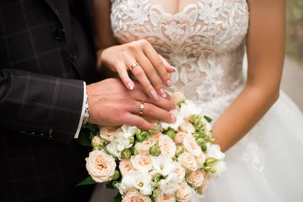 Handen van bruid en bruidegom met ringen op bruiloft boeket. Huwelijksconcept — Stockfoto