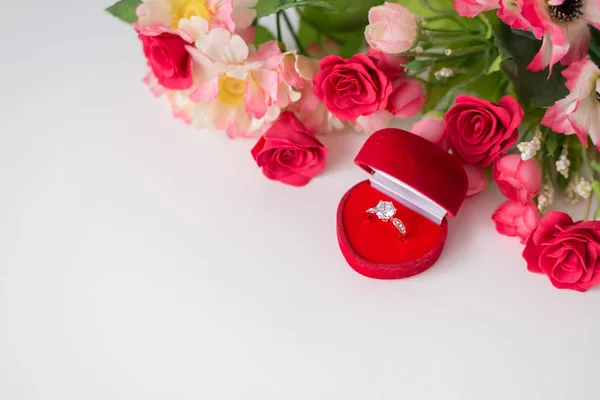 Anel de diamante em uma caixa em forma de coração vermelho com flores em um fundo branco. Espaço para SMS. Aniversário, Dia dos Namorados, noivado, presente de dia da mãe — Fotografia de Stock