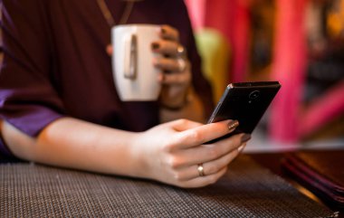 Kafede, dizüstü bilgisayarla çalış ve kahve iç. Kadın elleri telefona bakar. Bağımsız bir çalışanın uzaktan çalışması