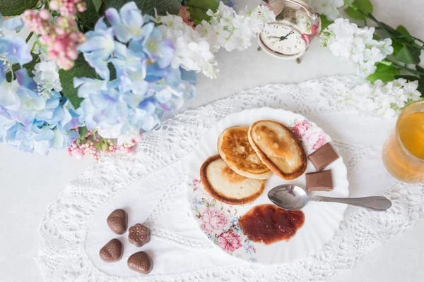 On the table with flowers pancakes with jam, green tea and sweets. Worth an alarm clock, the concept of Breakfast and sweet life — 스톡 사진