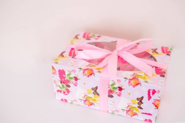Çiçek desenli hediye kutusu ve beyaz arka planda pembe kurdele..