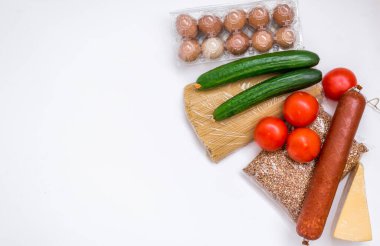 Beyaz arka planda bir dizi ürün. Market, sebze, tereyağı, yumurta ve sosis. Yiyecek paketi.