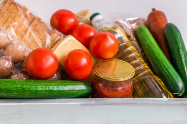 .Bağış kutusu ve yiyecek. Koronavirüs salgını sırasında insani yardım. İçinde gerekli şeyler, makarna, mısır gevreği ve sebzeler olan bir kutu.