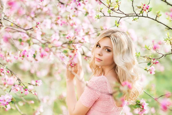 Bahar bahçesindeki güzel sarışın bir kızın portresi. Pembe Elma çiçekleri