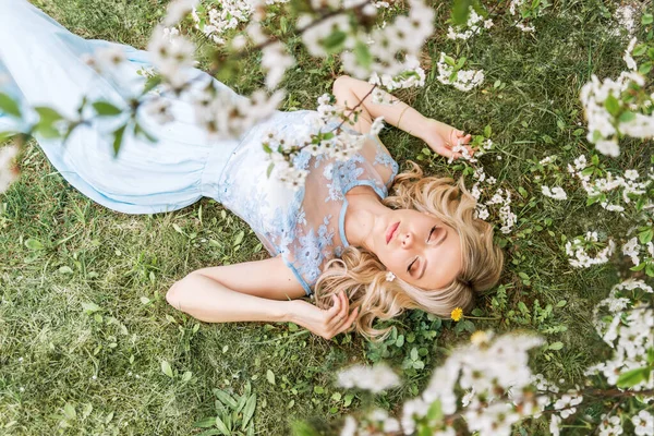 穿着长裙的漂亮女人躺在春天花园的草地上 — 图库照片