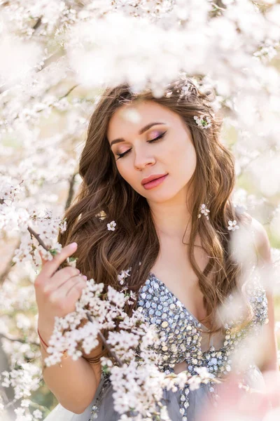 Çiçekli bir bahar bahçesinde hamile bir kadının portresi..