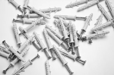 Beyaz arka plana saçılmış birkaç vida çapası kaotik bir pozisyonda yatıyor. Tamir ve montaj için vidaları olan plastik tıkaçlar.