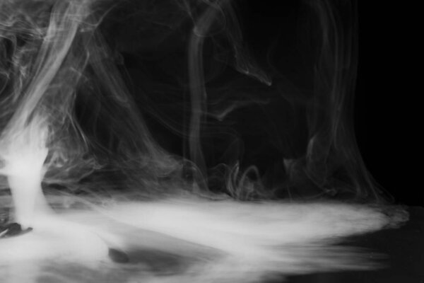 Smoke, fog or steam on black background. Mist that spreads across the surface and swirls in the air.