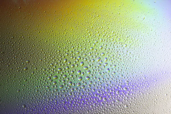 Water drops on glass with colorful rainbow background. Morning dew on the window with a refractive reflection of multicolored sunlight. — Stock Photo, Image