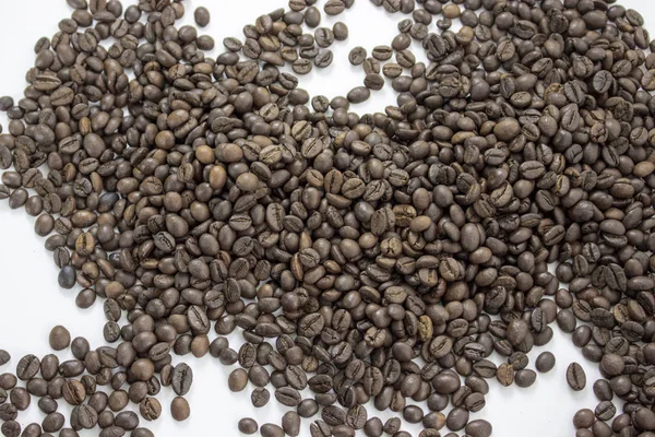 Granos de café asados esparcidos sobre un fondo blanco —  Fotos de Stock