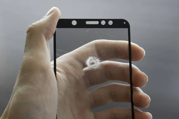 Broken protective glass of smartphone with cracks in hand on black background. — 图库照片