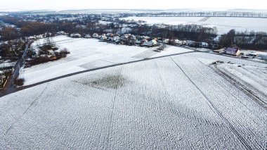 İlkbaharda kar yağdı. Küçük bir yerleşim yerinin havadan görünüşü. Tarım ve karla kaplı tarlalar kötü hasat verecek.