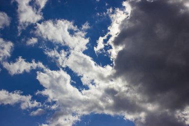 Koyu bulutların arkasındaki güneş, mavi güzel gökyüzü arka planına karşı..