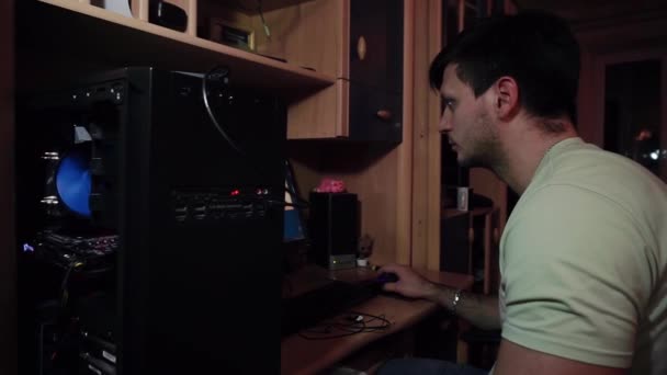 Adam parçalanmış bir sistem ünitesinde oturuyor, bir bilgisayar, çalışıyor. — Stok video