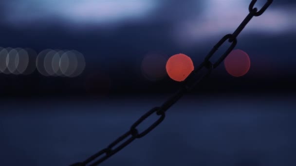 Heavy chain on a blue background with blurry lights in the night city — Stock Video
