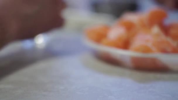 Gros plan. Les mains des gens tirent une assiette avec des tranches de mandarine l'un à l'autre 