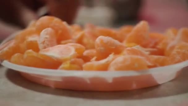 Close-up, as mãos dos povos mover prato com fatias de tangerina um para o outro. Citrinos, tangerinas ou laranjas . — Vídeo de Stock