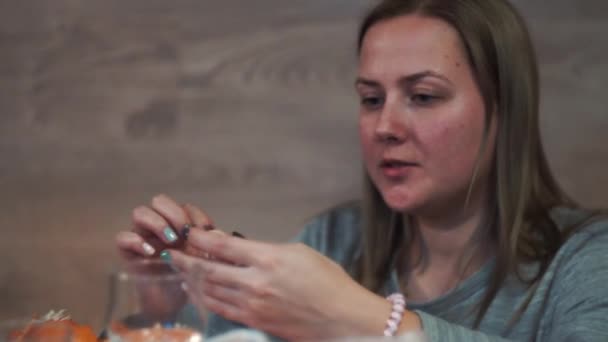 Close-up, a girl is cleaning mandarin at a party — Stock Video