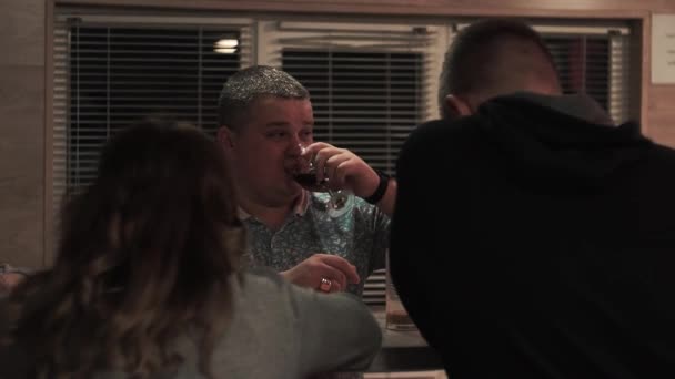 Confident man drinks from a glass and talks, talks, with friends at a party. — Stock Video