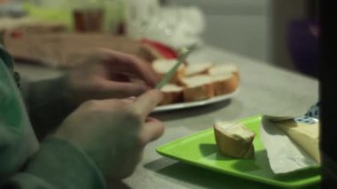 Kadının Close-Up smear tereyağı bir parça ekmek, bir bıçak kullanarak üzerinde eller. Sandviç.