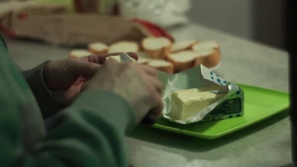 Las manos masculinas ponen la mantequilla sobre el pan picado en la velada. Cámara detrás por detrás — Vídeo de stock