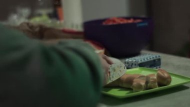 A guy s hand cuts a white loaf into pieces with a white knife at a party.
