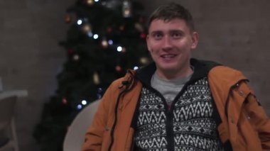 teary-eyed, red-eyed guy trying laugh laugh, smile party. Christmas tree background