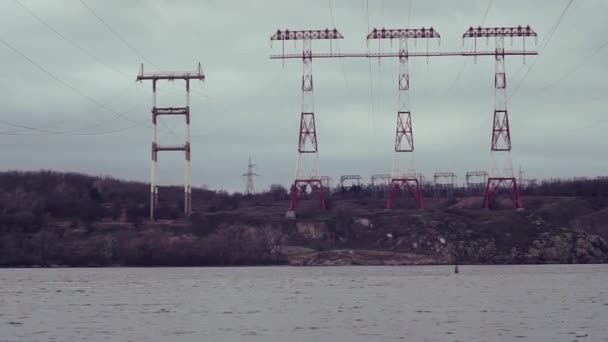 3 Power lines with crane-white foundations on the other side river, rocks. Spring, winter, autumn, cold — 비디오