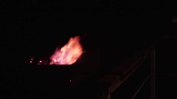 La nuit, dans la rue, dans le brasero, le bois de chauffage brûle d'une flamme rouge-bleue, dans l'obscurité absolue. Tir à la main 