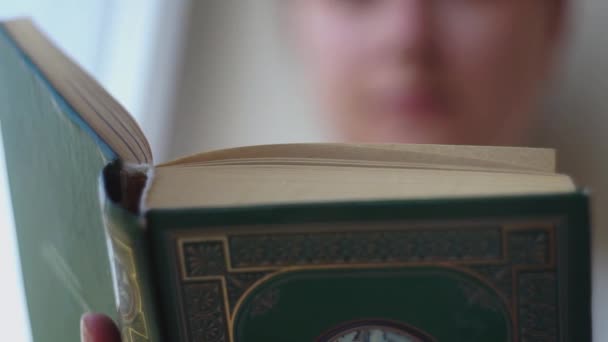 Close-up of the spine, cover of a thick art book, reads a girl in the background — Stock Video