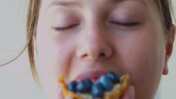Menina bonita, comendo uma cesta de bagas com mirtilos e sorrindo — Vídeo de Stock