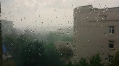 Islak ve bulutlu havada hastane penceresinden aşağı büyük bahar yağmuru damlaları akıyor.
