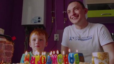 KIEV, UKRAINE - 18 Mayıs 2019 Mutlu baba ve oğlu, gülümsüyor, mumlu pastaya bakıyor