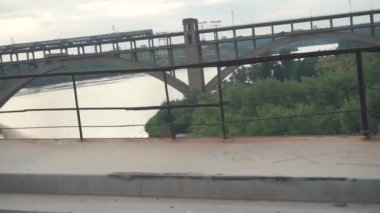 Gün batımında nehir üzerinde karayolu olan bir köprüde tren yolculuğu.