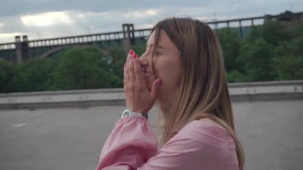 Mooi meisje lacht, verstopt zich achter haar hand. Een loopt over de brug.. — Stockvideo