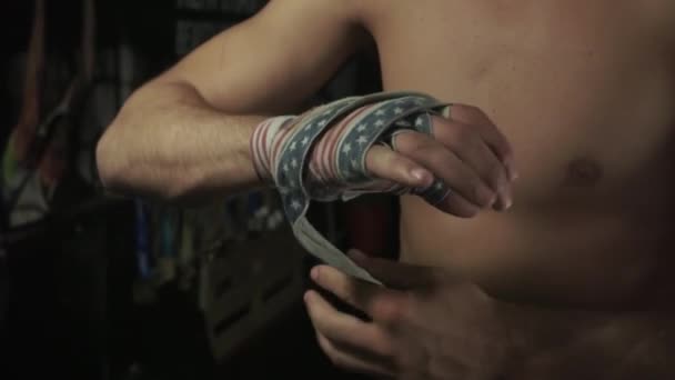 Movimento lento. Boxer com tronco nu envolve ligaduras com bandeira americana seu crepúsculo mão direita — Vídeo de Stock