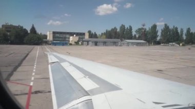 Uçak dönüyor, pistte dönüyor, asfalt eski havaalanını soyuyor. Kanat görünümü