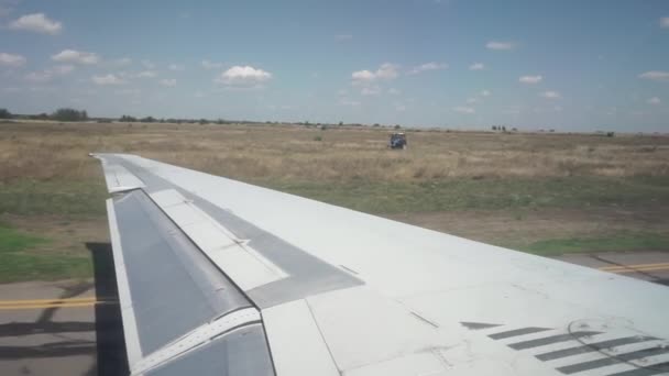 เครื่องบินปีกยาวสีขาวเคลื่อนที่ไปตามรันเวย์ รถแทรกเตอร์ สนามบนพื้นหลัง — วีดีโอสต็อก