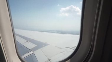 Pencereden uçan bir uçağın kanadını ve gökyüzünü görebilirsin.